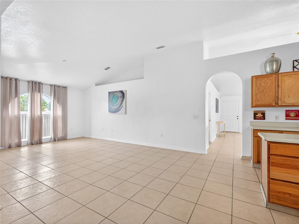 A spacious room features light-colored tile flooring, white walls, and an arched entryway — 2589 HUNLEY LOOP, KISSIMMEE, FL