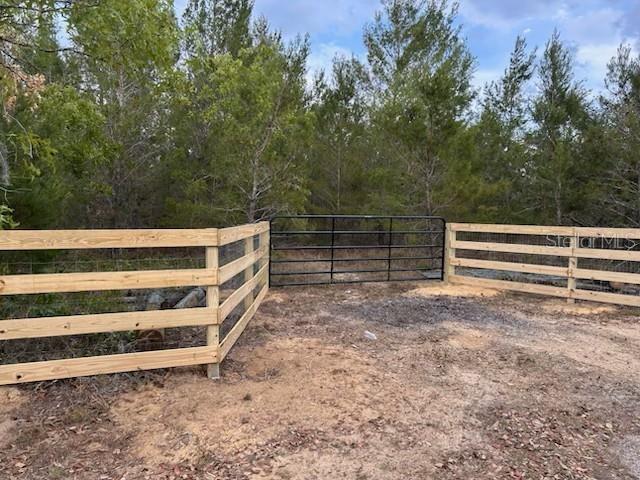 A black metal gate is centered between two sections of wooden post-and-rail fencing — 9940 BLACK BEAR LANE, WINTER GARDEN, FL