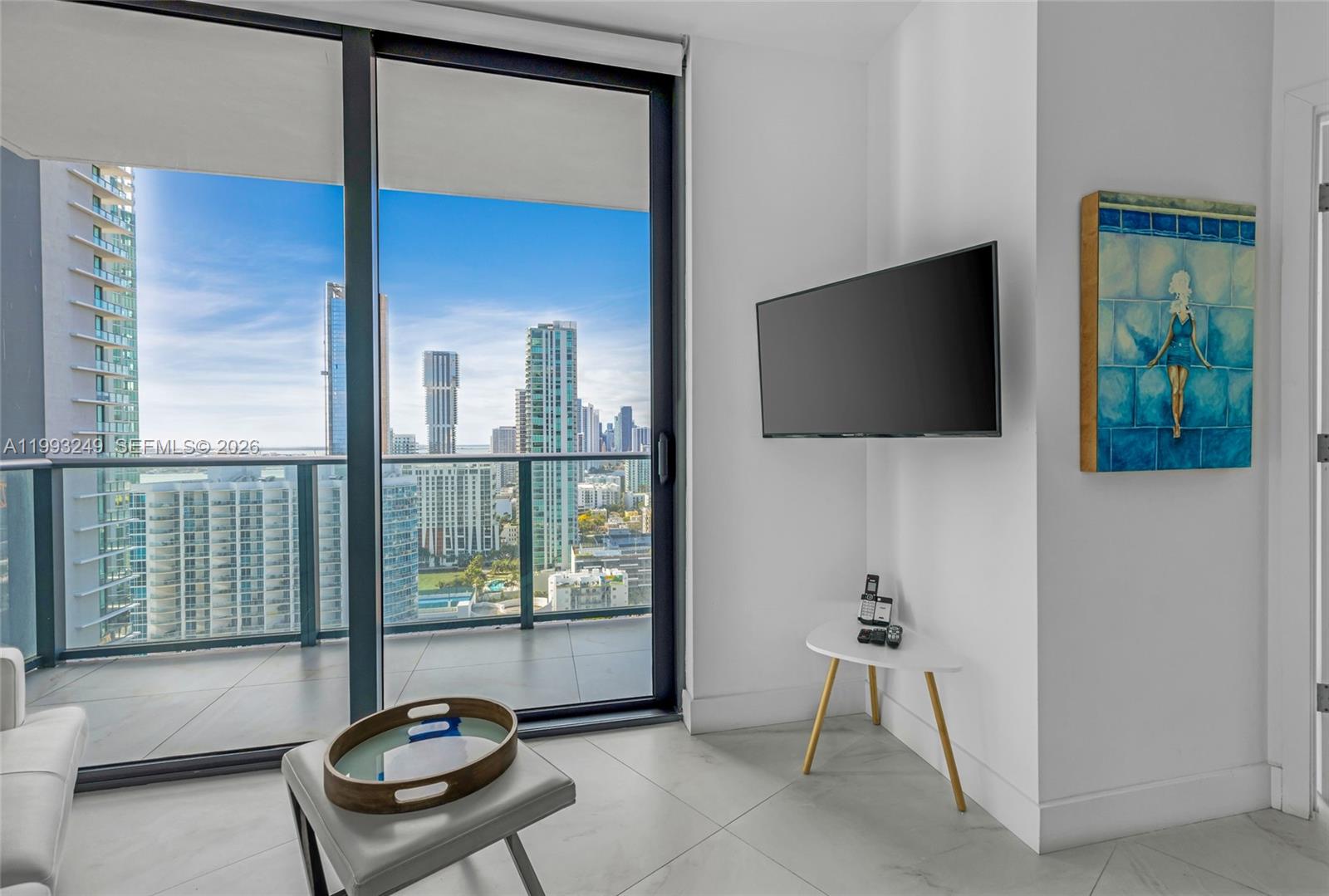 A modern living room features a wall-mounted television, a small side table, and a balcony — 501 NE 31 St # 2407, Miami FL 33137, MIAMI, FL