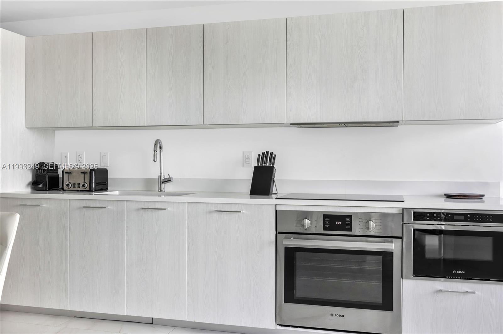 A modern kitchen features light wood-grain cabinets, white countertops, and stainless steel Bosch appliances — 501 NE 31 St # 2407, Miami FL 33137, MIAMI, FL