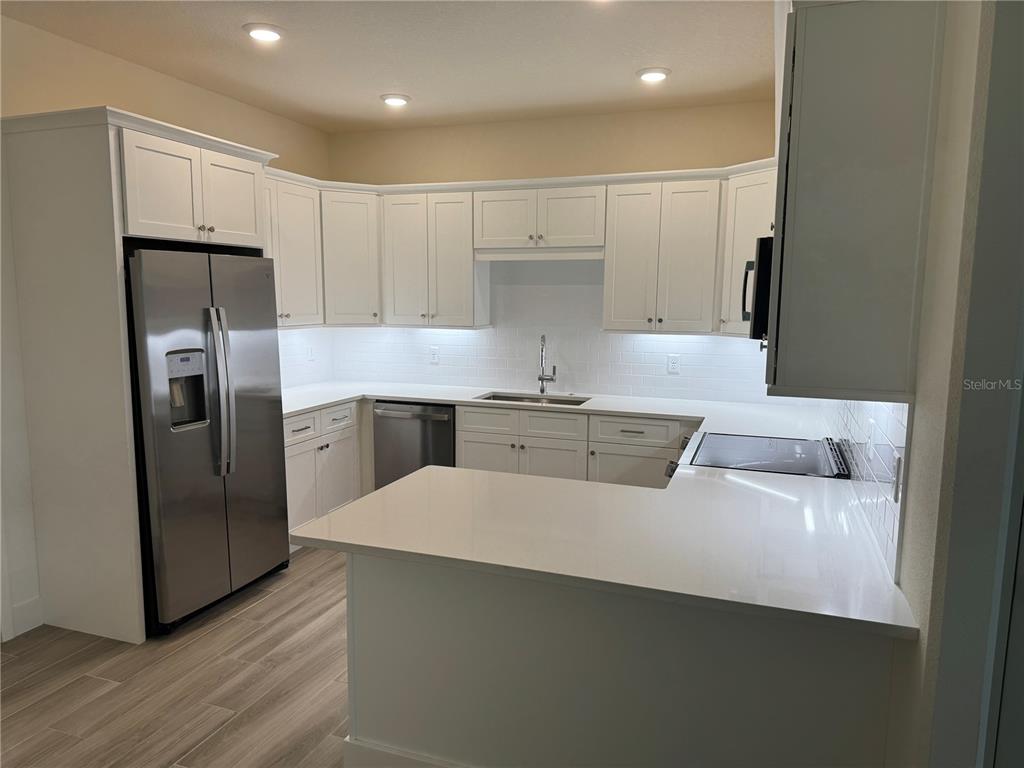 A modern kitchen features white cabinetry, stainless steel appliances, and white quartz countertops — 3057 ISLES WAY, NEW SMYRNA BEACH, FL