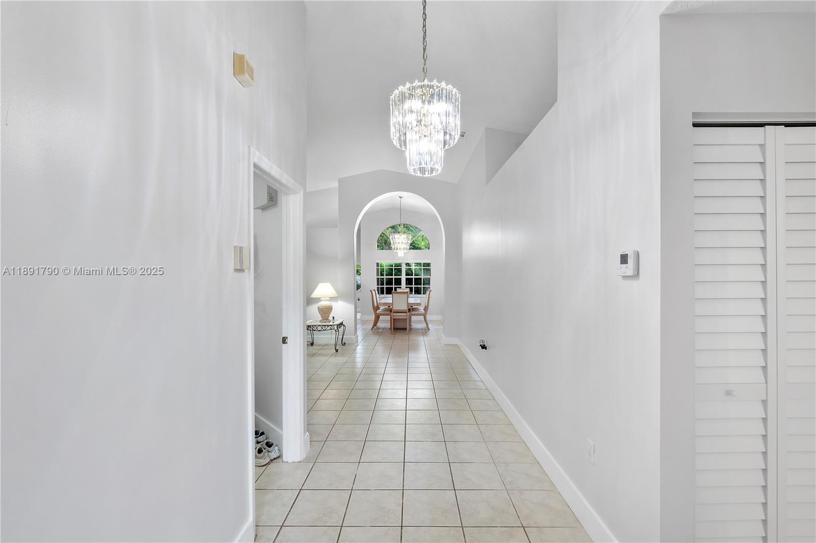 A tiled hallway leads to a dining area with an arched window and crystal chandelier — 10350 SW 166th Ct, Miami FL 33196, MIAMI, FL