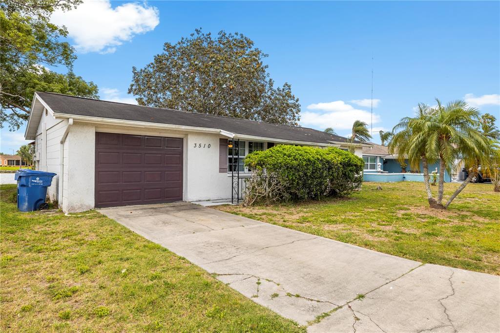 A single-story house with a white exterior, a brown garage door, and a concrete driveway — 3510 WILSON DRIVE, HOLIDAY, FL