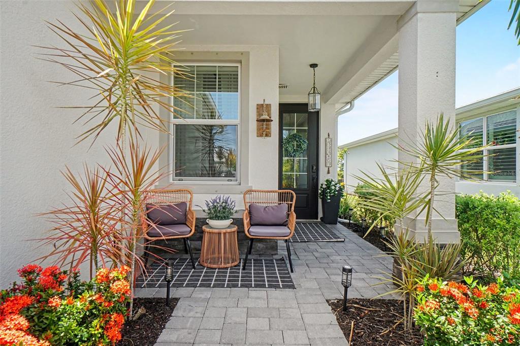 A front porch features two wicker chairs, a small table, and potted plants — 43789 CATTLEMAN DRIVE, PUNTA GORDA, FL