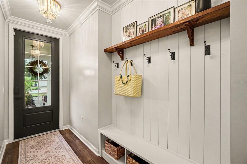 An entryway features a black front door, a built-in bench, and a wooden wall shelf — 43789 CATTLEMAN DRIVE, PUNTA GORDA, FL