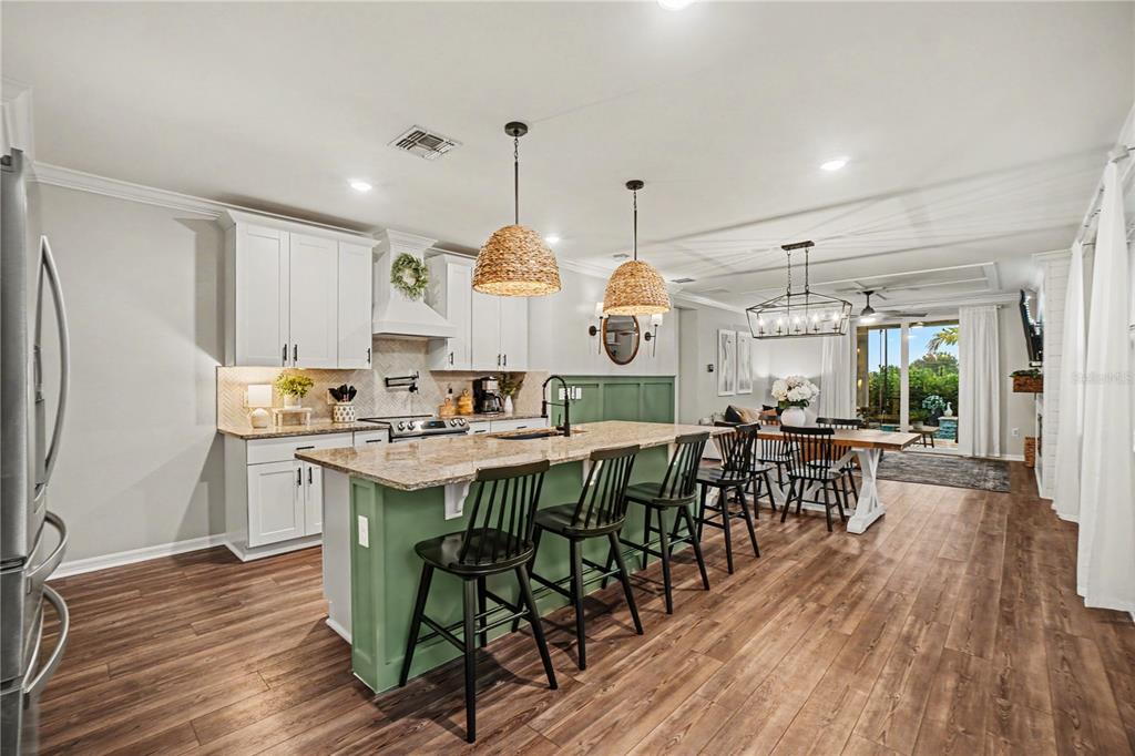 A kitchen with white cabinets, a green island, and a dining area with wood floors — 43789 CATTLEMAN DRIVE, PUNTA GORDA, FL
