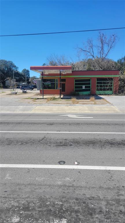A single-story commercial building with a red facade and two garage bays sits roadside — 10 NW 250TH STREET, NEWBERRY, FL