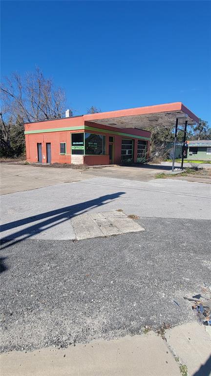 An exterior view of a vacant, orange-painted commercial building with a large, flat canopy — 10 NW 250TH STREET, NEWBERRY, FL
