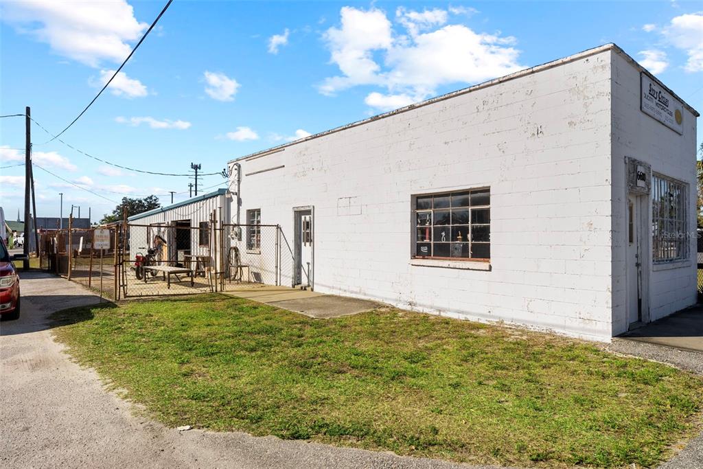 A white concrete block commercial building features a fenced side yard and a small lawn — 6600 HAINES ROAD N, ST PETERSBURG, FL