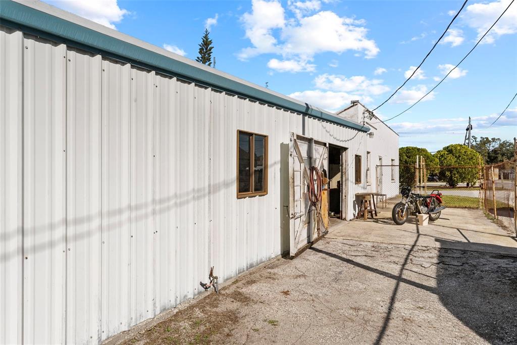 An exterior view of a metal-sided building with a motorcycle parked on a concrete lot — 6600 HAINES ROAD N, ST PETERSBURG, FL