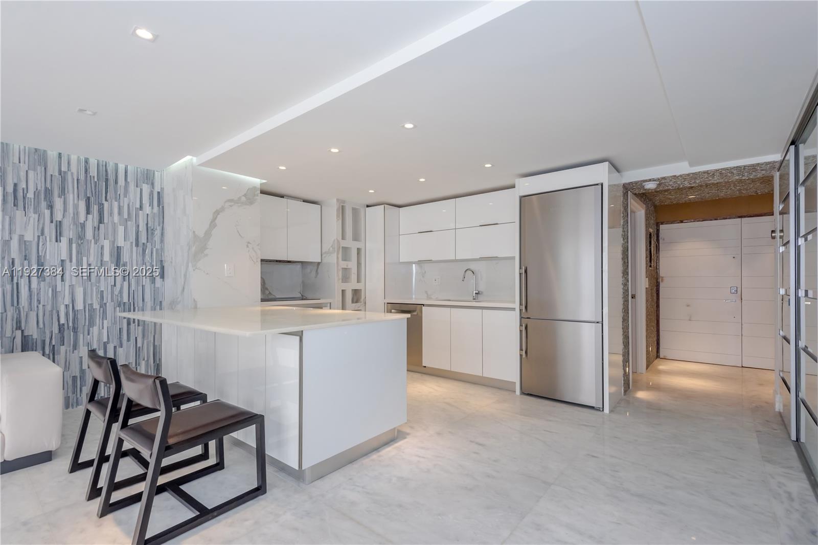 A modern kitchen features white cabinetry, a marble island, stainless steel appliances, and tile flooring — 6423 Collins Ave # 304, Miami Beach FL 33141, MIAMI BEACH, FL