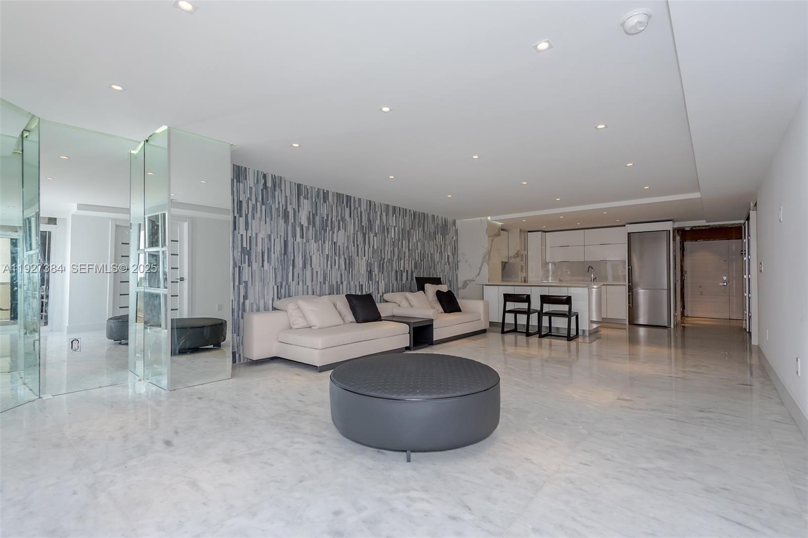 An open-concept living room features marble floors, a textured accent wall, and a modern kitchen — 6423 Collins Ave # 304, Miami Beach FL 33141, MIAMI BEACH, FL