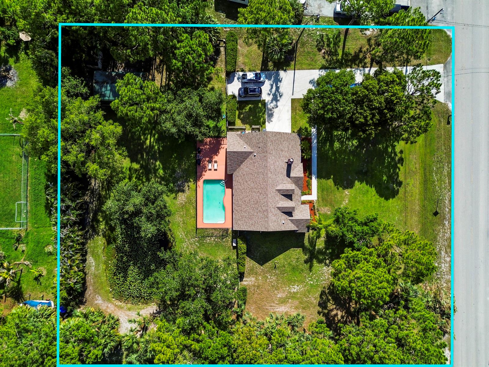 An aerial view shows a house with a swimming pool, patio, and driveway on a lot — 15286 Key Lime Boulevard, Loxahatchee FL 33470, LOXAHATCHEE, FL