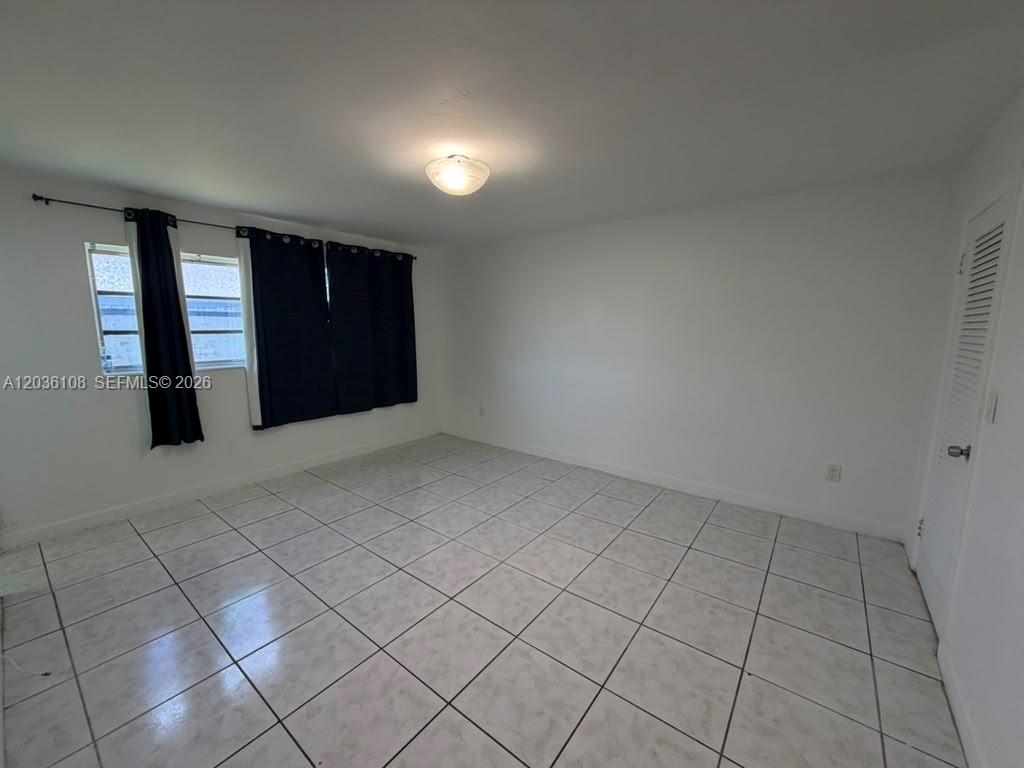 An empty room features white walls, a tiled floor, a ceiling light, and dark curtains — 1885 NE 121st St # 8, North Miami FL 33181, NORTH MIAMI, FL