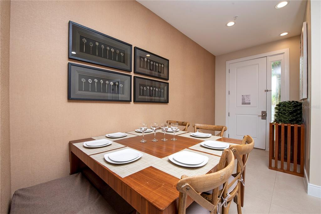 A dining room features a square wooden table, four chairs, a bench, and framed wall art — 7673 RECIFE DRIVE, KISSIMMEE, FL