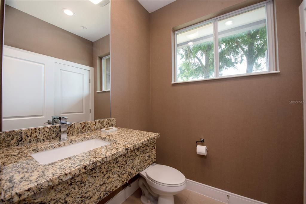A bathroom features a granite vanity countertop, a white sink, a mirror, and a toilet — 7673 RECIFE DRIVE, KISSIMMEE, FL