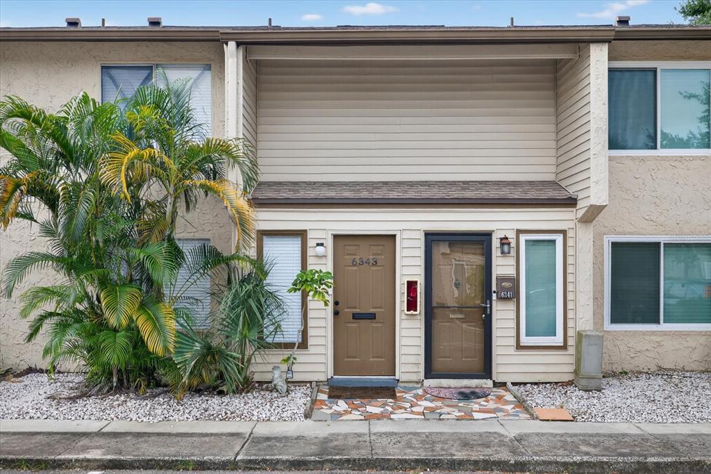 The exterior of a two-story townhouse features tan siding, two front doors, and a palm tree — 6343 23RD STREET N, ST PETERSBURG, FL