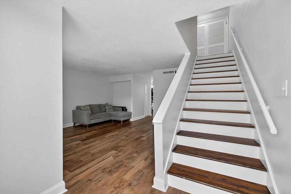 A living room with wood flooring and a staircase leading to an upper level — 6343 23RD STREET N, ST PETERSBURG, FL