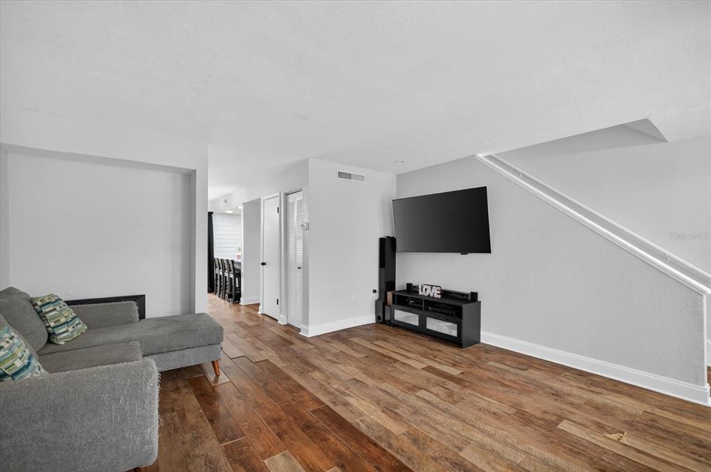 A living room features gray walls, wood-look flooring, a sectional sofa, and a wall-mounted television — 6343 23RD STREET N, ST PETERSBURG, FL