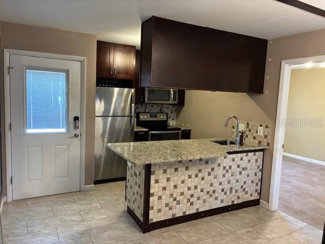 A kitchen features a granite-topped island, stainless steel appliances, and a tiled breakfast bar — 3806 N OAK DRIVE UNIT V21, TAMPA, FL