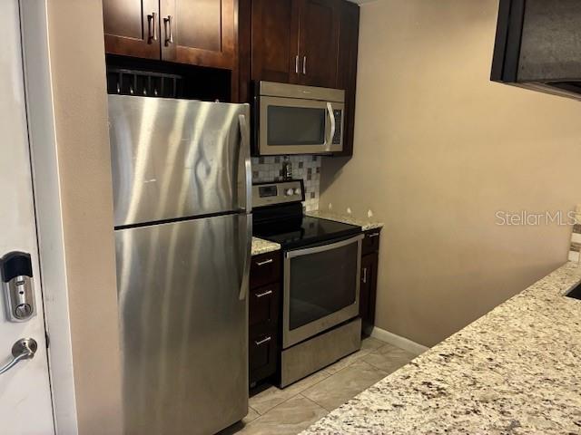 A kitchen features stainless steel appliances, dark wood cabinets, and granite countertops — 3806 N OAK DRIVE UNIT V21, TAMPA, FL