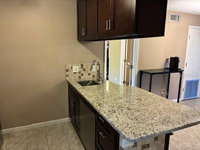 A kitchen features dark wood cabinets, granite countertops, and a tiled backsplash — 3806 N OAK DRIVE UNIT V21, TAMPA, FL
