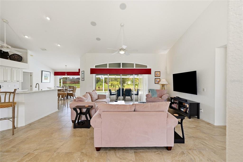 A living room with light tile floors, pink sofas, and a sliding door to a patio — 816 BOUNDARY BOULEVARD, ROTONDA WEST, FL
