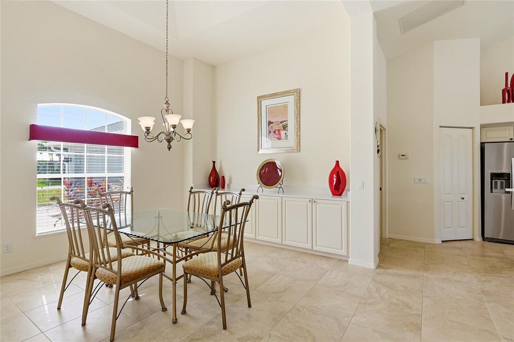 A dining room with a glass table, metal chairs, tile floors, and built-in white cabinets — 816 BOUNDARY BOULEVARD, ROTONDA WEST, FL