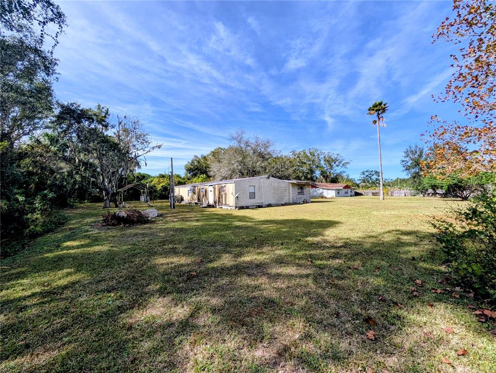 A single-story mobile home sits on a large, grassy lot with trees and a palm — 8412 PETERSON ROAD, ODESSA, FL