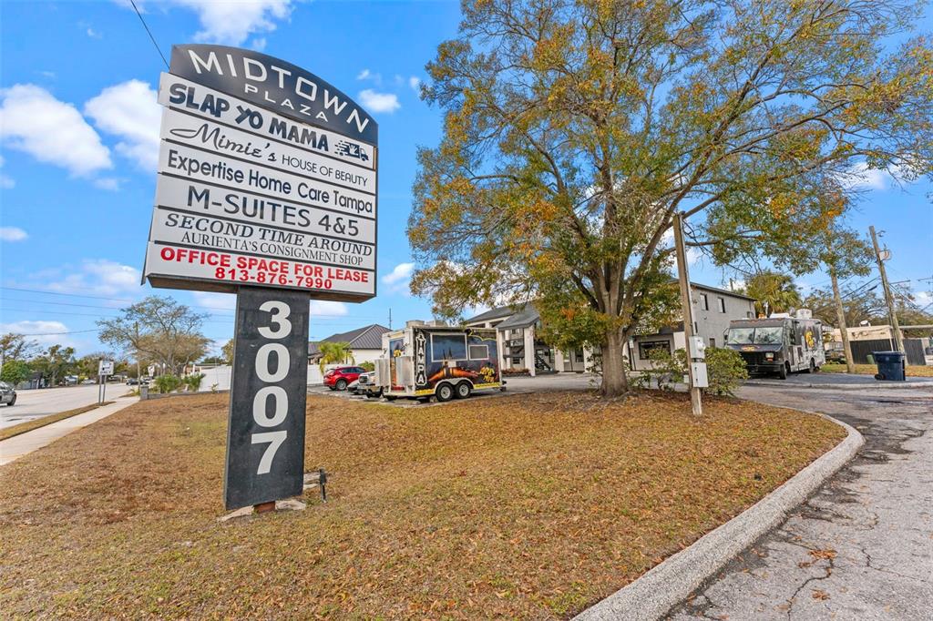 A sign for Midtown Plaza stands in front of a building with food trucks parked nearby — 3007 W CYPRESS STREET, TAMPA, FL
