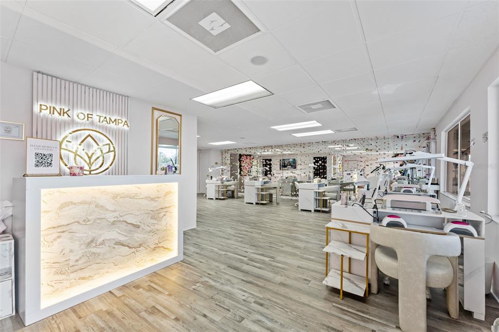A bright nail salon features a marble-fronted reception desk, wood-look flooring, and multiple manicure stations — 3007 W CYPRESS STREET, TAMPA, FL