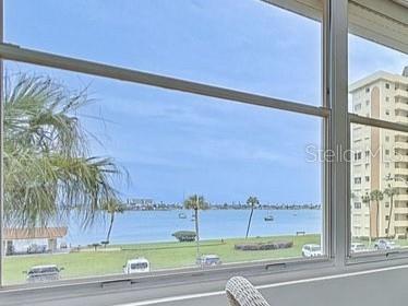 A view of a waterfront area with palm trees and a tall building through a window — 4550 COVE CIRCLE UNIT 302, ST PETERSBURG, FL