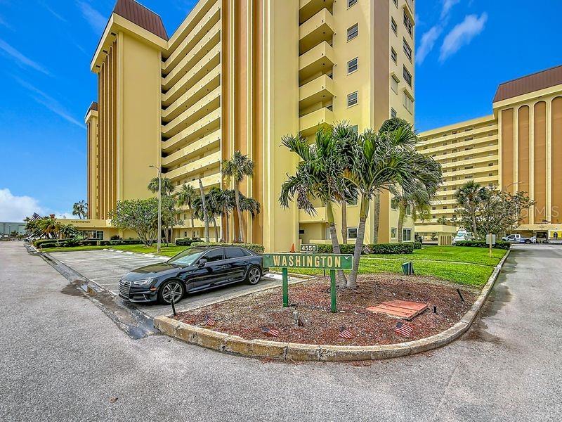 A black sedan is parked in front of a tall, yellow apartment building — 4550 COVE CIRCLE UNIT 302, ST PETERSBURG, FL