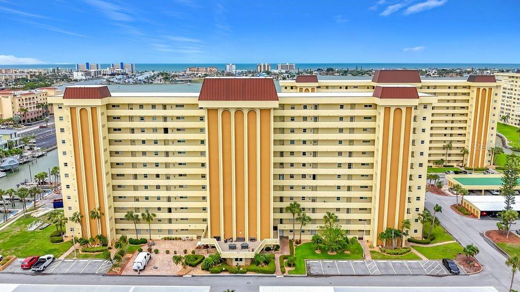 An aerial view of a multi-story yellow apartment building with a brown roof — 4550 COVE CIRCLE UNIT 302, ST PETERSBURG, FL