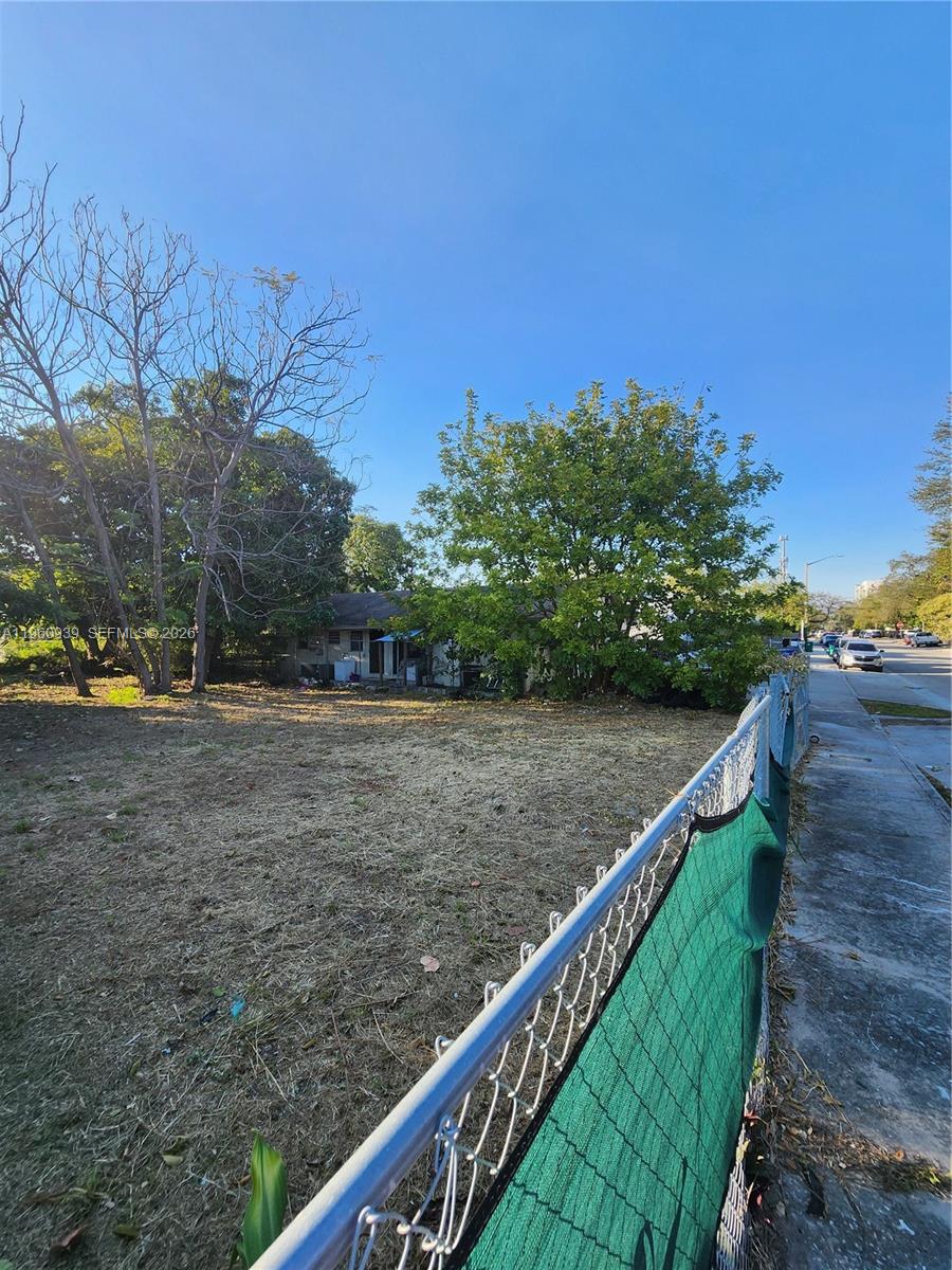 A vacant, grassy lot sits next to a sidewalk with a house in the background — 6742 NW 4th Ave, Miami FL 33150, MIAMI, FL
