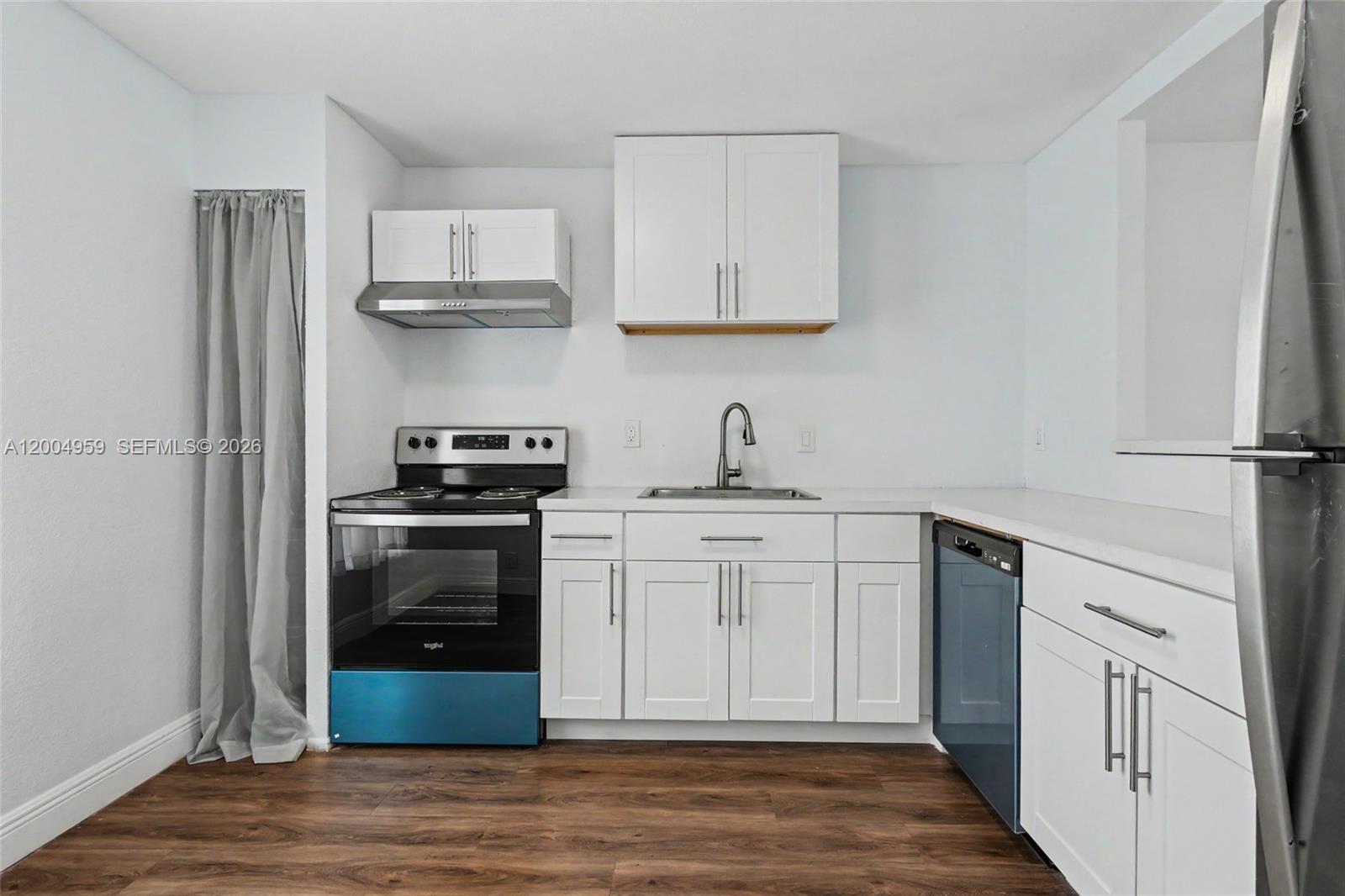 A kitchen features white cabinets, stainless steel appliances, a sink, and dark wood-look flooring — 1402 NW 80th Ave # 302, Margate FL 33063, MARGATE, FL