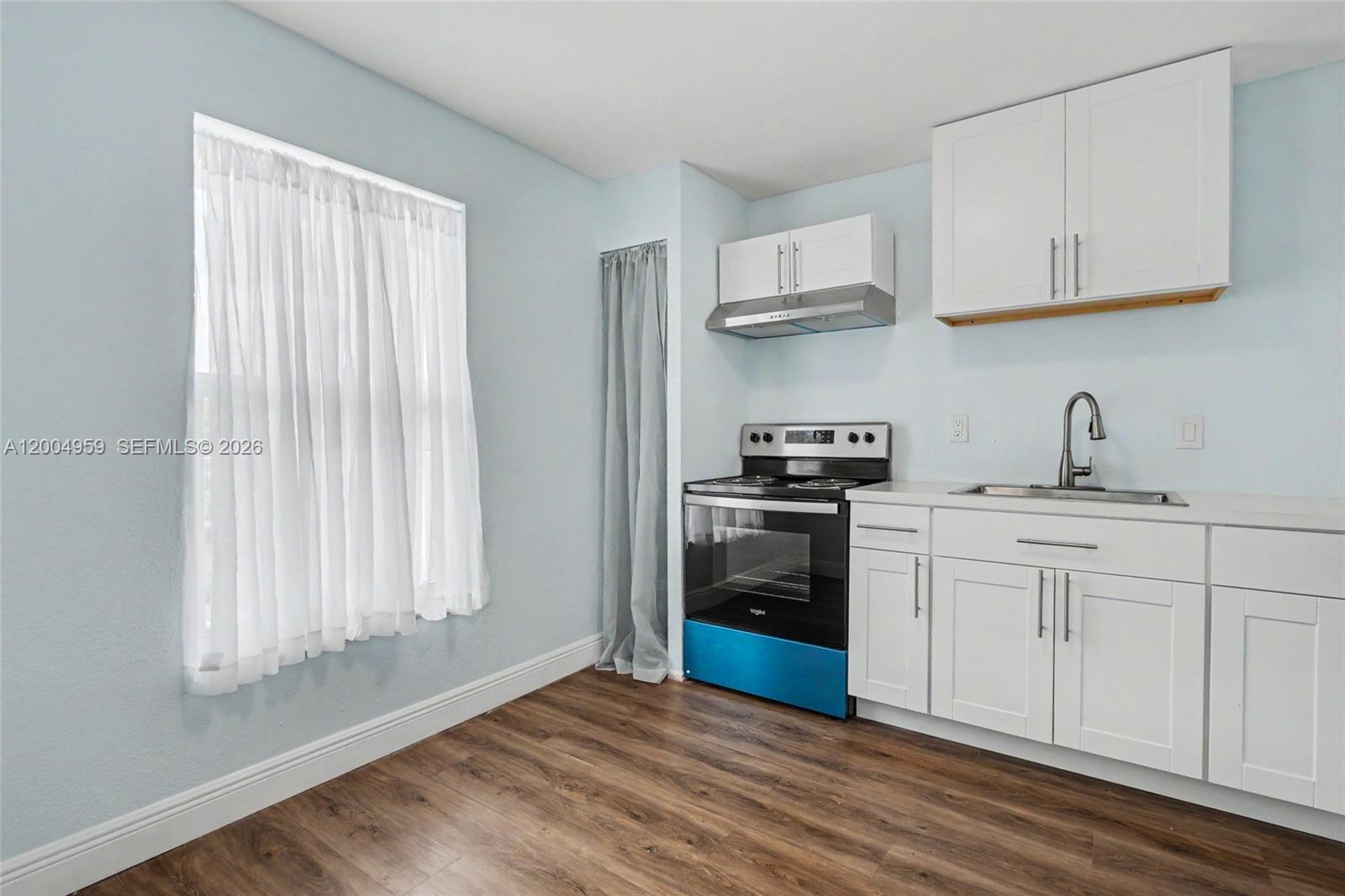 A small kitchen features white cabinets, a stainless steel stove, and light blue walls — 1402 NW 80th Ave # 302, Margate FL 33063, MARGATE, FL