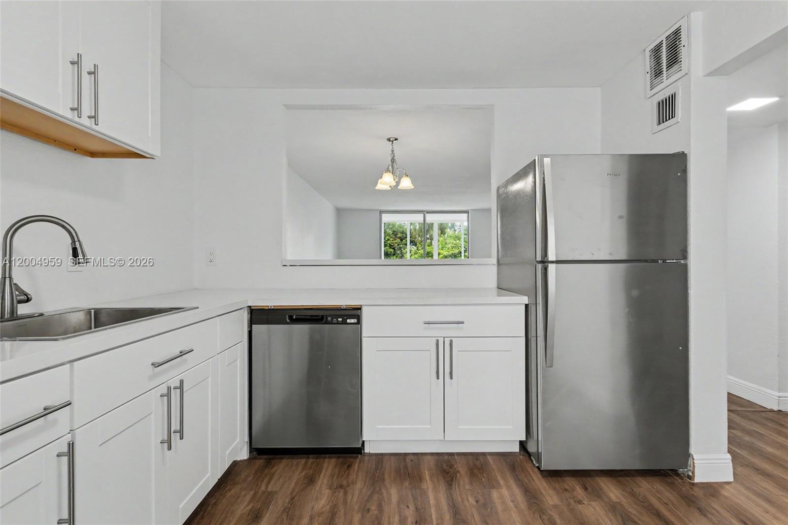 A kitchen features white cabinets, stainless steel appliances, and a pass-through window to another room — 1402 NW 80th Ave # 302, Margate FL 33063, MARGATE, FL