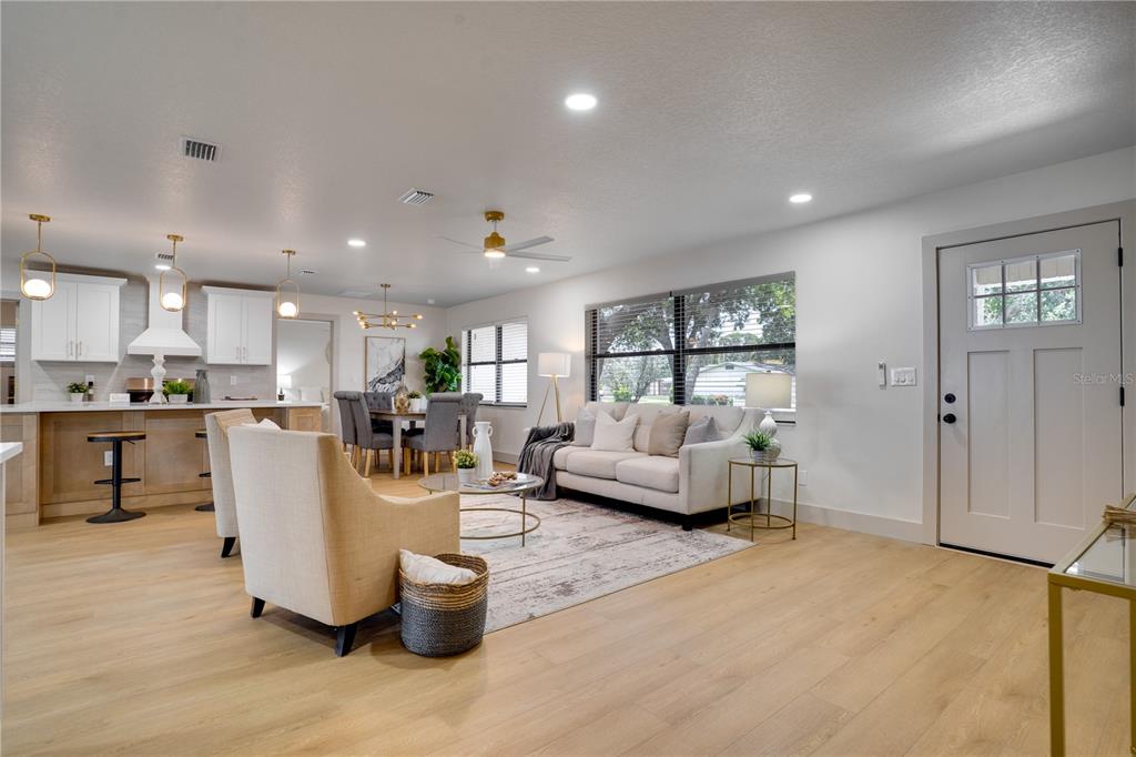 An open-concept living and dining area features light wood flooring, white cabinetry, and neutral furniture — 2239 68TH AVENUE N, ST PETERSBURG, FL