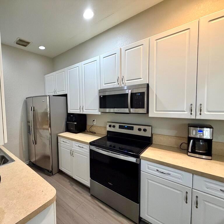 A kitchen features white cabinets, stainless steel appliances, and light-colored countertops — 2403 NW 7th Street, Boynton Beach FL 33426, BOYNTON BEACH, FL