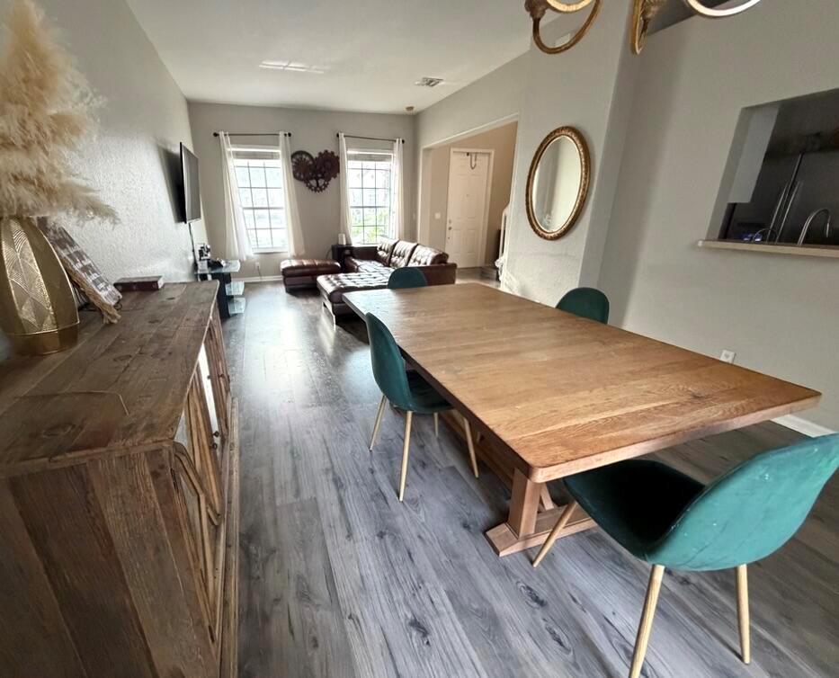 A dining area with a wooden table and green chairs opens into a living room — 2403 NW 7th Street, Boynton Beach FL 33426, BOYNTON BEACH, FL