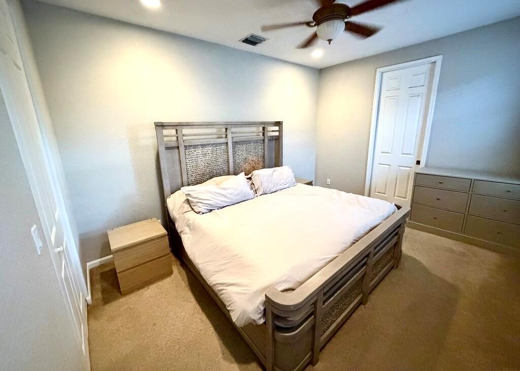 A bedroom features a wooden bed frame, a nightstand, and a dresser on carpeted flooring — 2403 NW 7th Street, Boynton Beach FL 33426, BOYNTON BEACH, FL
