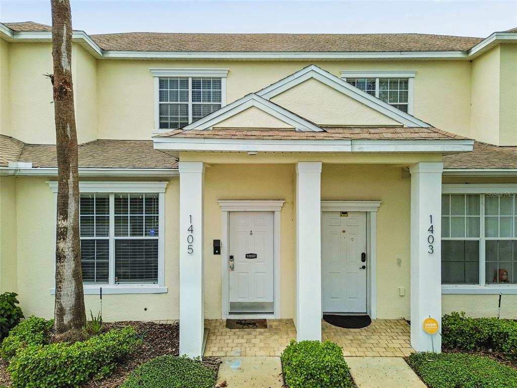 The exterior of a two-story townhouse features yellow stucco walls and two white entry doors — 1405 RETREAT CIRCLE, CLERMONT, FL