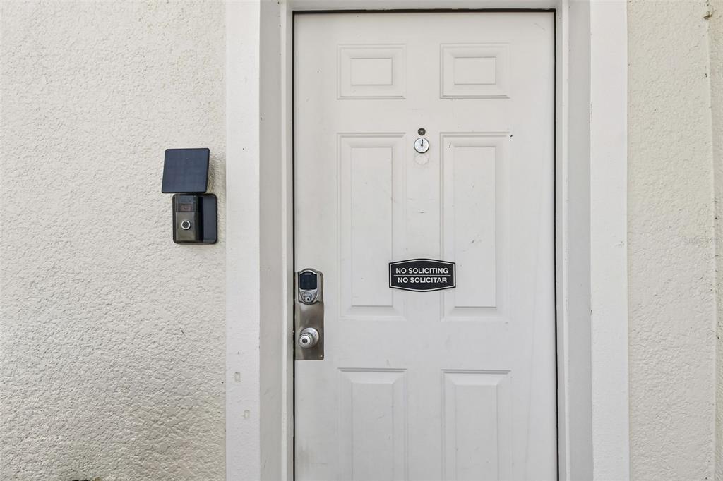 A white exterior door features a smart doorbell, a digital lock, and a no soliciting sign — 1405 RETREAT CIRCLE, CLERMONT, FL