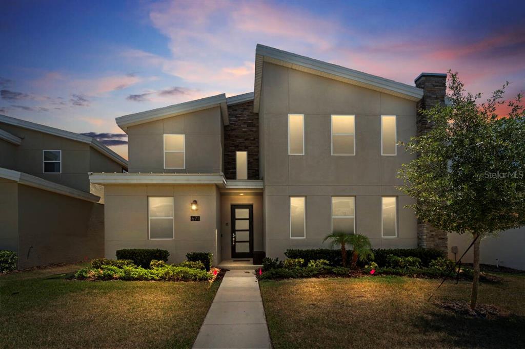 A two-story modern house with a stone accent wall and a concrete walkway at dusk — 671 STICKS STREET, DAVENPORT, FL