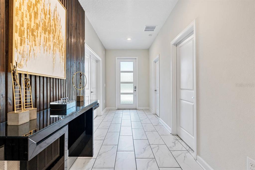 A hallway with white tile floors, a dark wood slat wall, and a glass-paneled door — 671 STICKS STREET, DAVENPORT, FL