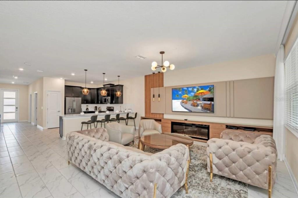 An open-concept living room features a tufted sofa, fireplace, and kitchen with a breakfast bar — 671 STICKS STREET, DAVENPORT, FL