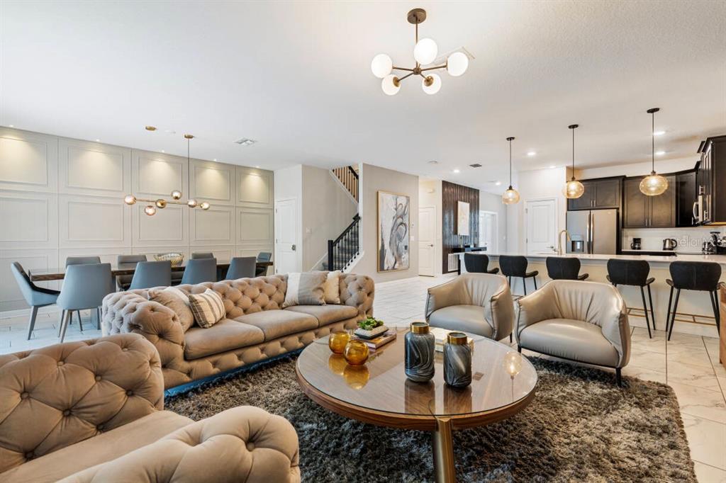 An open-concept living and dining area features a tufted sofa, round coffee table, and kitchen — 671 STICKS STREET, DAVENPORT, FL