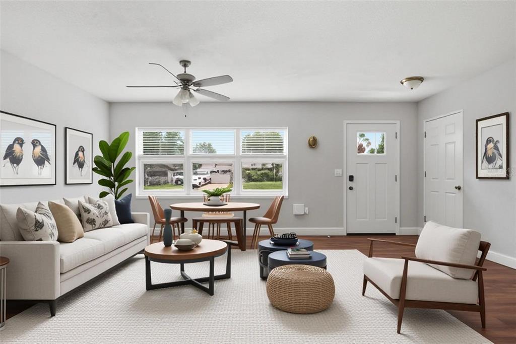 This is a digitally staged living room featuring a sofa, dining area, and front door — 917 KENSINGTON DRIVE, ORLANDO, FL