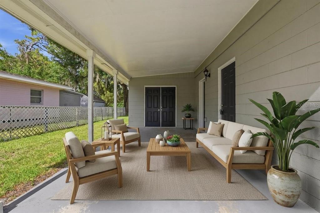 A covered patio features outdoor furniture, a rug, and a view of a fenced yard — 917 KENSINGTON DRIVE, ORLANDO, FL